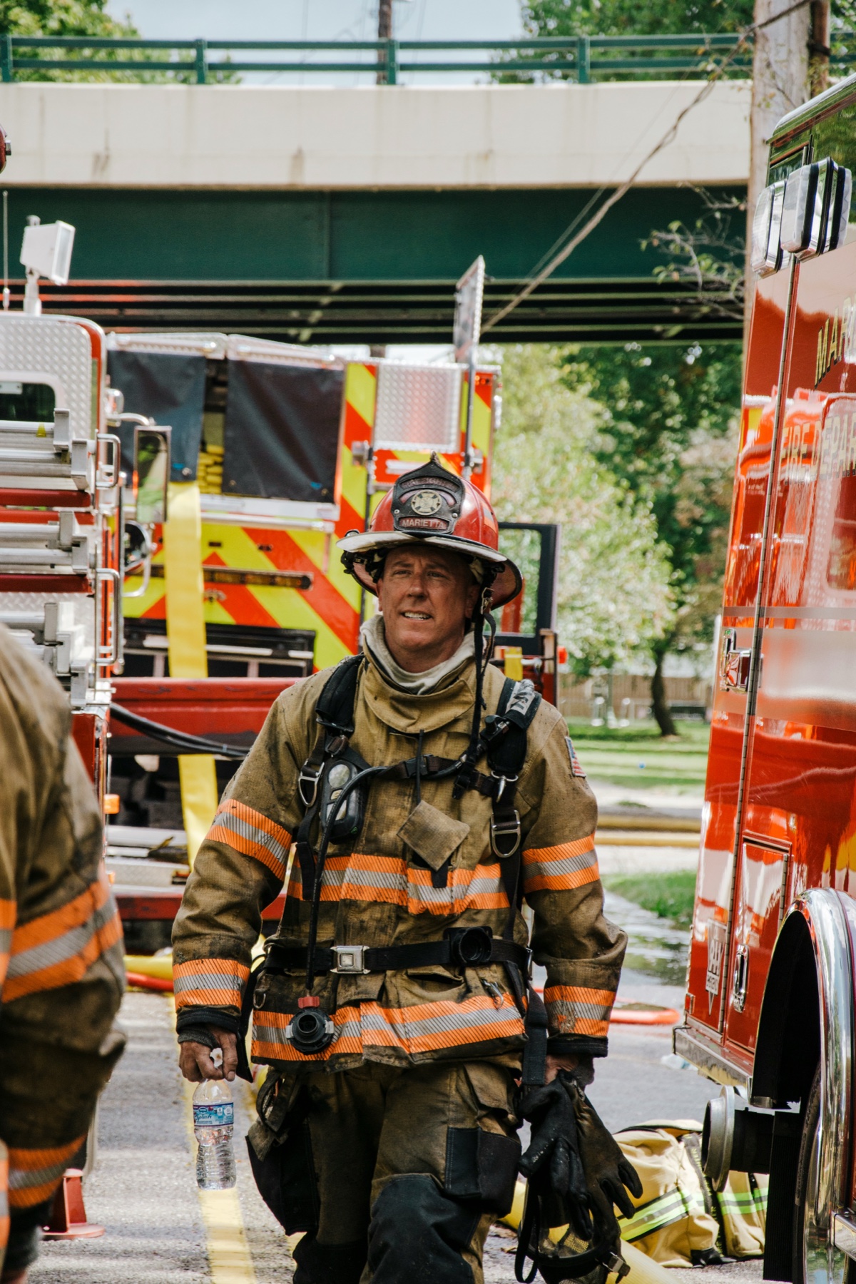 A firefighter in turnout gear standing beside an engine.